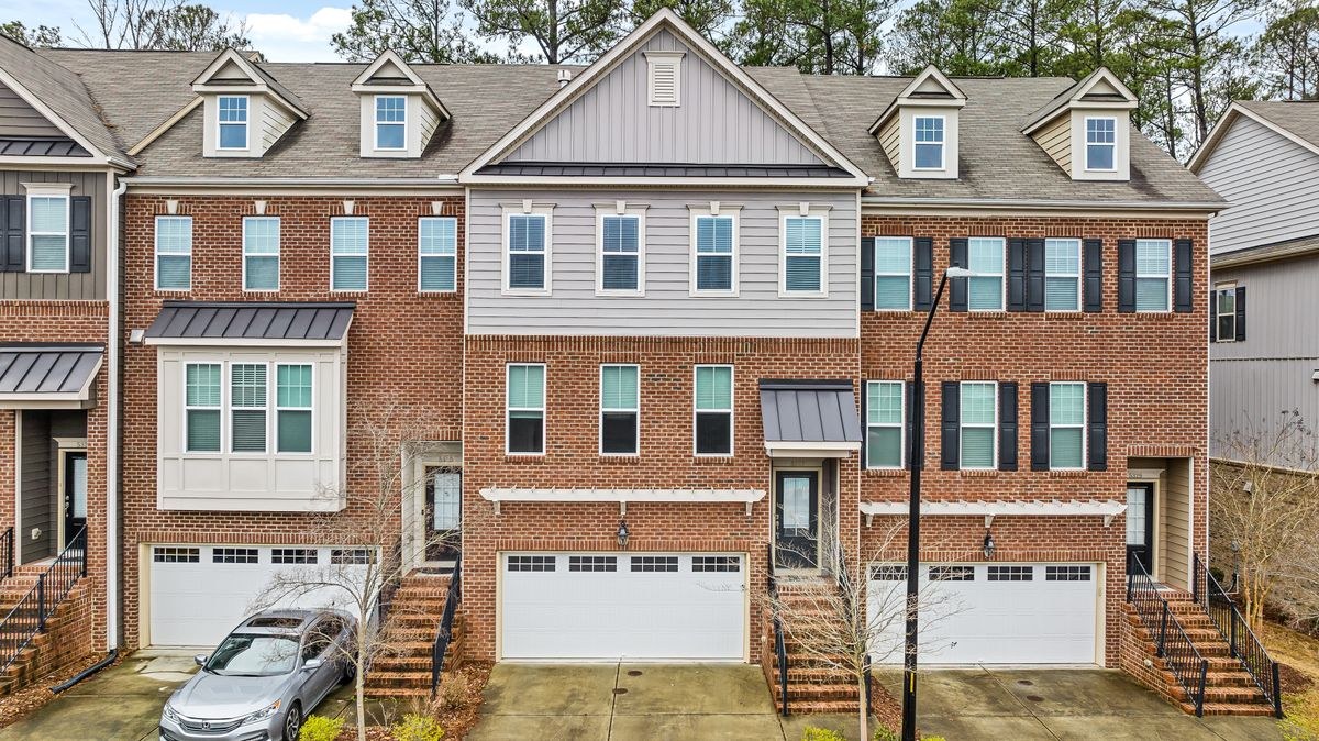 Row of three-storey brick townhouses with white garage doors and front stairs