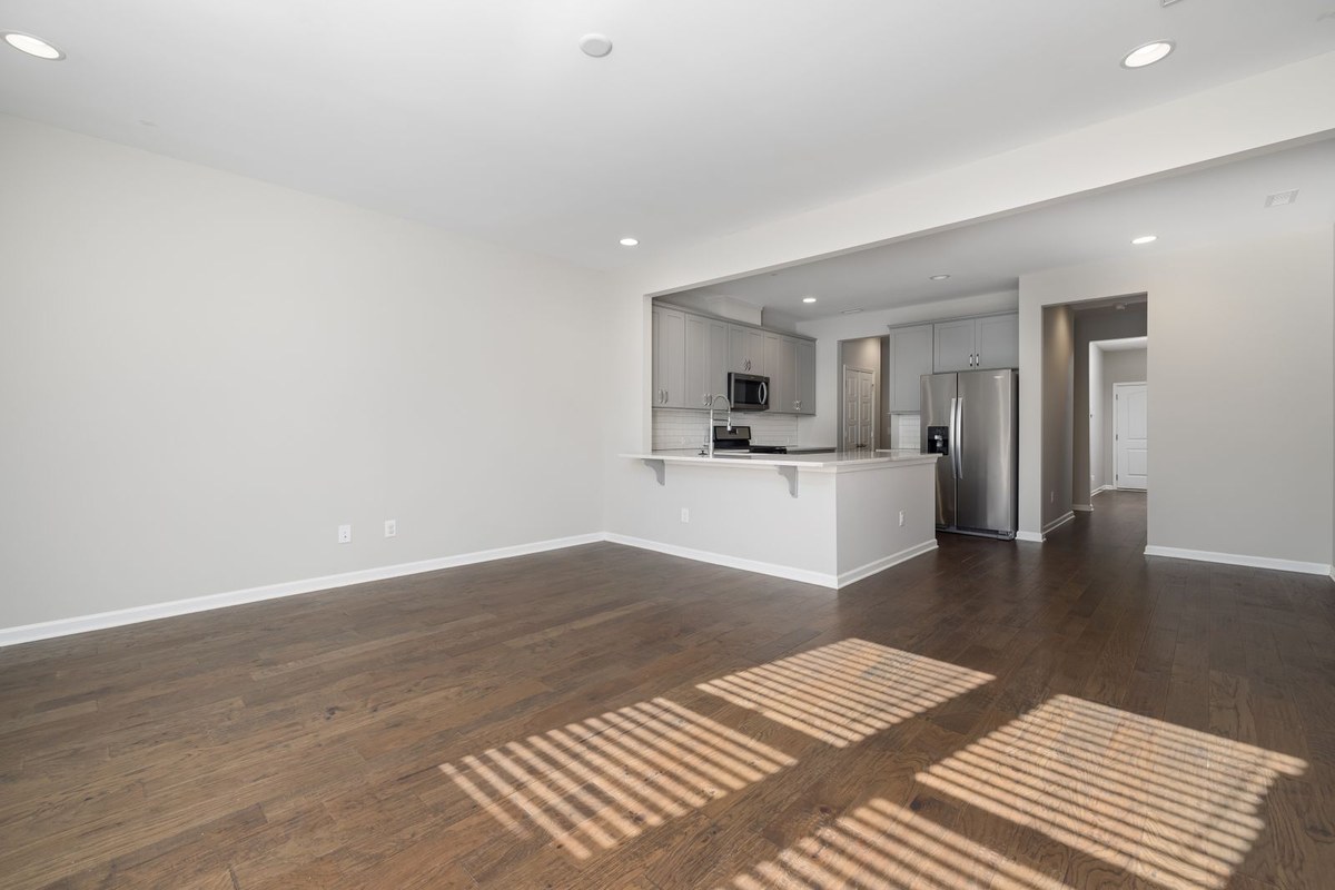 Empty open-plan apartment living area with grey kitchen cabinets and wood flooring